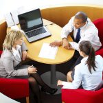 Three business employees discussing together. View from above.